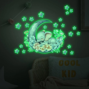 Luminous wall decal featuring a sleeping elephant on moon with stars in a dark bedroom