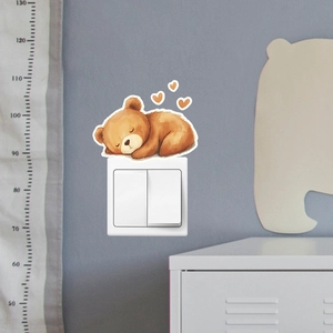 Glow-in-the-dark sleeping bear wall sticker placed above a white light switch in a nursery