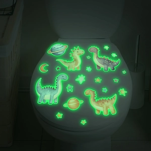 Luminous cartoon dinosaur and star wall stickers glowing green on a toilet lid in the dark