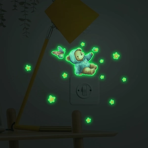 Luminous cartoon bear and stars wall stickers glowing green in a dark bedroom