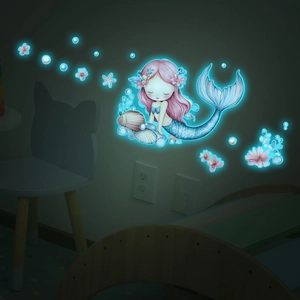 Detailed view of luminous mermaid and shell wall decals glowing in dark blue light