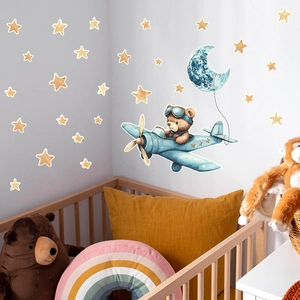 Luminous cartoon bear flying plane with stars wall decals in a cozy nursery bedroom