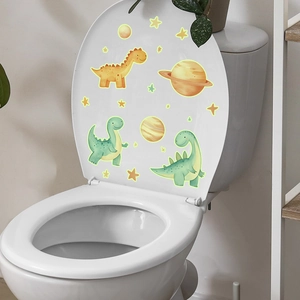 Detail showing glowing cute cartoon dinosaur stickers on a white toilet lid in bathroom