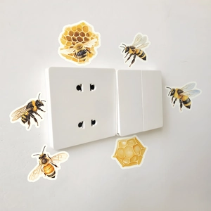 Detailed view of glowing bee and honeycomb stickers applied around a light switch