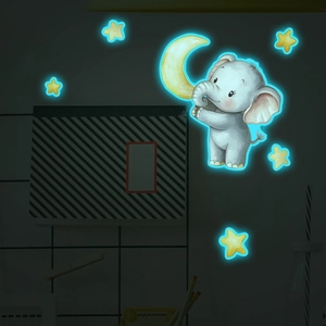 Luminous wall decal showing a cute blue elephant holding a moon and glowing stars in the dark