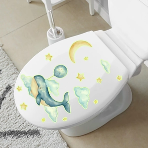 Stickers muraux lumineux avec baleine endormie, lune jaune et nuages verts sur une toilette