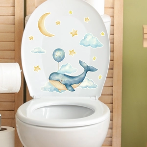 Détail des autocollants baleine bleue et lune sur un abattant de WC blanc propre