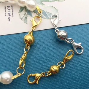Macro shot of gold and silver magnetic lobster clasps connecting a white pearl necklace