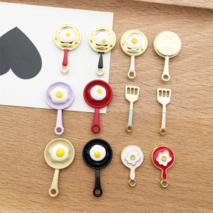 Macro detail of colorful enamel fried egg pan and spatula charms for DIY jewelry making