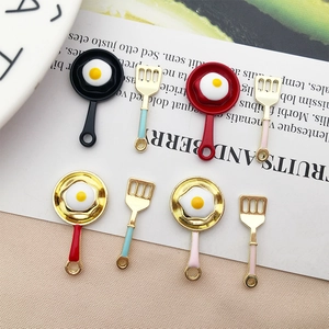 Flat lay macro of colorful enamel frying pan and spatula charms for DIY jewelry making