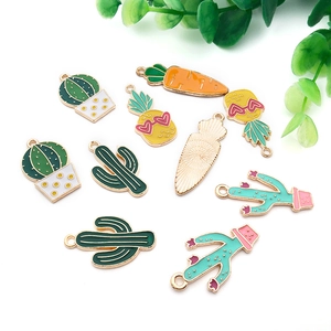 Vue détaillée de breloques émaillées cactus et ananas avec bords dorés en alliage