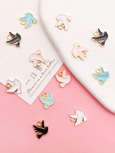 Vue à plat de breloques oiseaux colorées blanc rose bleu noir sur plateau cœur