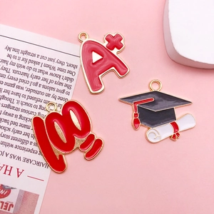 Detailed macro view of Graduation enamel alloy charms featuring A+ score and doctoral cap