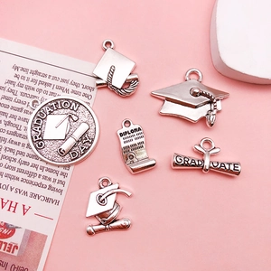 Detail of vintage silver graduation charms with diploma and mortarboard cap designs