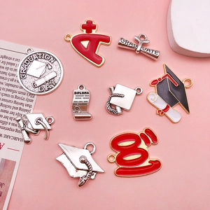 Detailed view of alloy graduation charms with mortarboard and A+ icons on pink surface