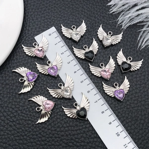 Macro shot of 21mm heart wings pendants on black leather with a ruler for size reference