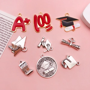 Macro shot of assorted graduation alloy charms with A+ motifs and doctoral caps on pink