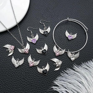 Silver winged heart jewelry set with colorful gems on black leather background