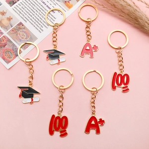 Detailed macro view of enamel graduation charms with A+ and 100 motifs on gold keychains