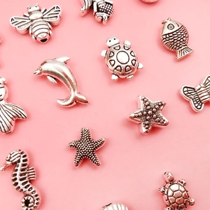 Macro-opname van vintage zilveren dierbedels voor DIY-sieraden op een roze achtergrond
