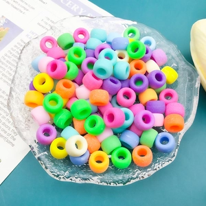 Macro shot of colorful matte acrylic beads with large holes in a textured glass bowl
