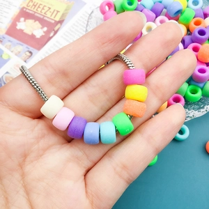 Macro shot of colorful acrylic barrel beads on a snake chain bracelet in pastel macaron tones
