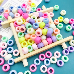 Macro detail of mixed macaron colored acrylic large hole beads in a small wooden tray