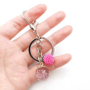Pink raspberry and dried flower glass bottle pendant keychain held by hand on white backdrop