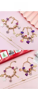 Close-up of golden Christmas charm bracelets with purple beads and festive alloy pendants