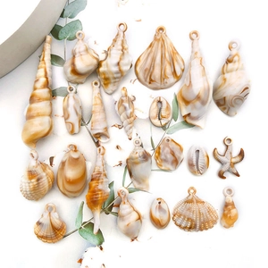 Gros plan de divers breloques en forme de coquillages en acrylique avec textures marbrées bicolores