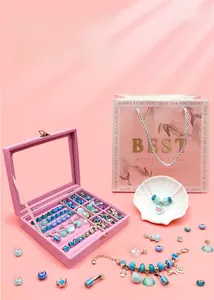 Close-up of pink jewelry box with blue DIY beads, dolphin charms and gift bag