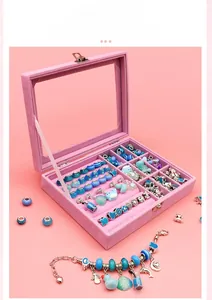 Detailed view of internal compartments in a pink velvet jewelry box with blue DIY beads