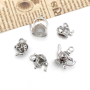 Detalle macro de cinco dijes de tetera de plata antigua para manualidades y joyería creativa