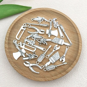 Macro detail of antique silver alloy tool charms including mini wrench and screwdriver