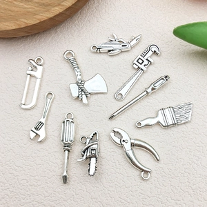 Close-up of vintage silver alloy miniature hardware tool pendants for DIY crafts