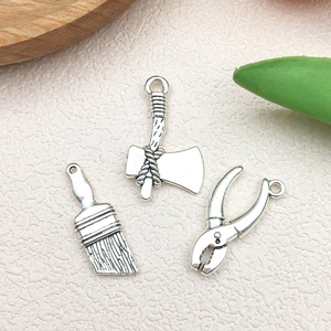 Detailed macro of antique silver alloy tool pendants including an axe, brush and pliers