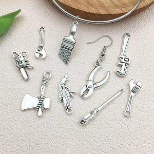 Collection of antique silver DIY alloy tool charms including wrench and pliers on a wooden tray