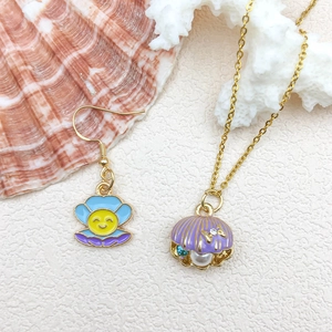Pastel shell jewelry set with gold necklace and earrings on ocean theme background