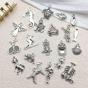 Collection of antique silver charms featuring owls, seahorses, and sports themes on beige