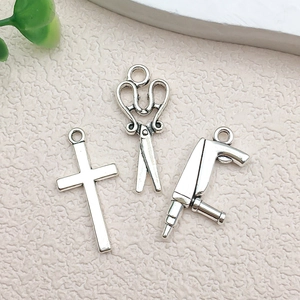 Macro view of vintage silver alloy charms featuring a cross, scissors and drill tool