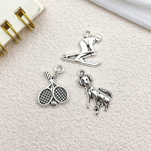 Detail of vintage silver metal charms featuring skier, tennis rackets, and a hunting dog