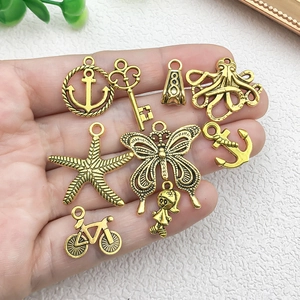 Assortiment antieke gouden legering bedeltjes met anker-, sleutel- en vlindervormen