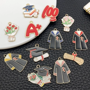 Detailed macro view of enamel graduation charms with mortarboard and scroll motifs