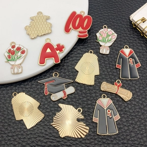 Detailed macro view of graduation enamel charms with gold plated backs and textured finish