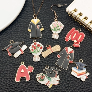 Detail of DIY alloy graduation charms including caps and gowns on black texture