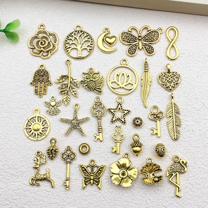 Flat lay of 28 vintage gold DIY jewelry charms including moon, tree and butterfly shapes