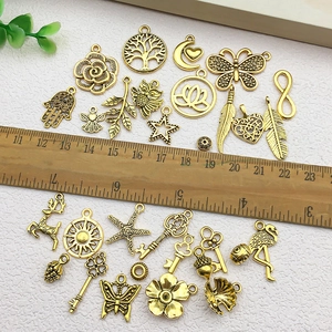 Detailed flat lay of vintage gold alloy charms in various shapes with a wood ruler for scale