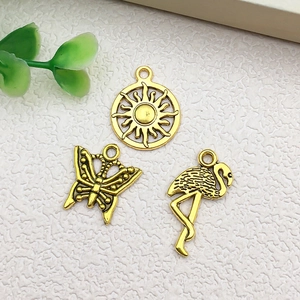 Detailed macro view of vintage gold alloy charms featuring sun, butterfly and flamingo shapes