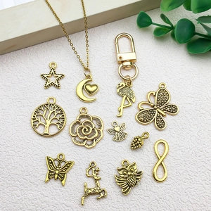 Assorted vintage gold alloy charms including butterfly, tree of life, and owl on white surface
