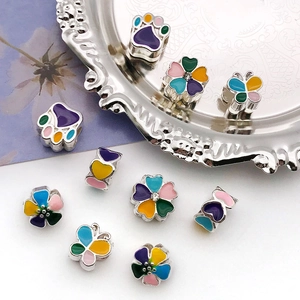 Macro shot of colorful enamel charms featuring floral and paw designs with silver metal finish